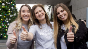 Nicole Hurd gives a thumbs up with two students