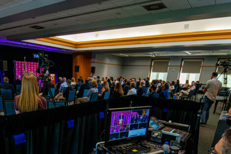 audience members sit in the Marlo Room, video equipment captures the event