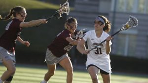 Kirsten Wilhelmsen '17 carries the ball in her stick while being defended by Colgate players in a women's lacrosse game.